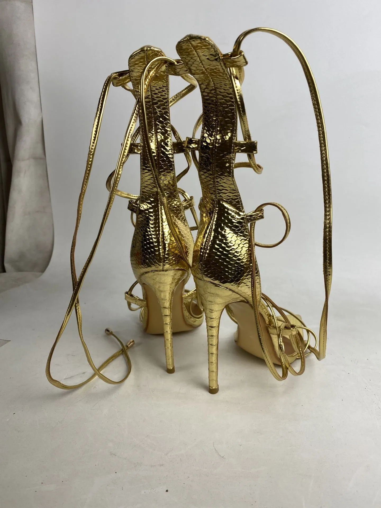 Pointed golden Roman cross strapped boots with thin heels