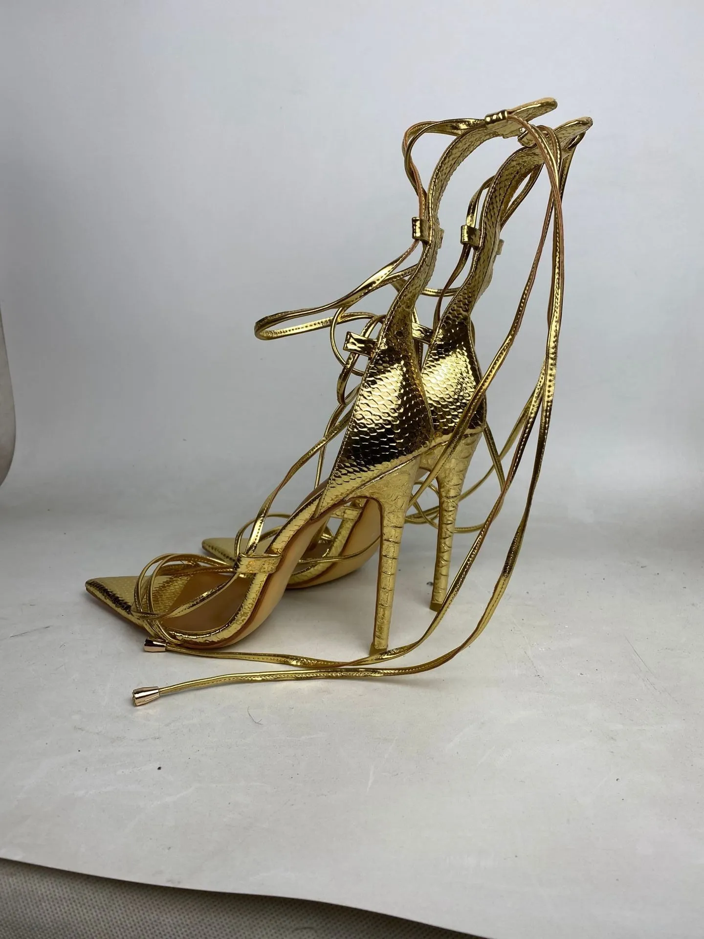 Pointed golden Roman cross strapped boots with thin heels